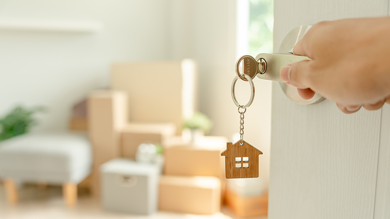 mano che apre la porta di casa con portachiavi a forma di casa